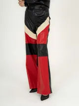Pantalón de cuero sintético negro con paneles en rojo y beige.