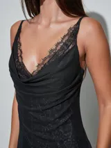 Vestido corto negro con sutil estampado animal print, escote en V con detalles de encaje y diseño cruzado drapeado en el torso.