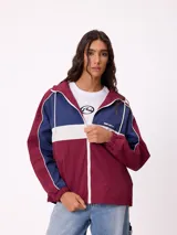 Campera rompevientos Rusty con diseño color block en tonos bordó, azul y blanco. Cuenta con cierre frontal, capucha con cordones ajustables, puños elásticos y logo bordado en el pecho.