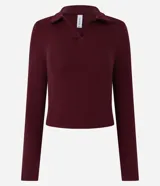 Blusa de manga larga confeccionada en tejido rib de algodón con cuello polo y escote en V. Presenta un diseño ajustado al cuerpo y acabado liso.