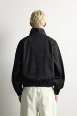 Sudadera de corte relajado confeccionada en denim de algodón con efecto lavado. Presenta cuello subido con cierre frontal de cremallera, manga larga con puños elásticos y bajo elástico. Incluye un bolsillo con cierre de cremallera en el pecho.