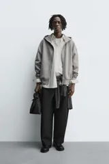 Sudadera de corte relajado confeccionada en tejido de algodón con interior afelpado. Presenta cierre frontal de cremallera, capucha con cuello subido, manga larga y acabados en rib.