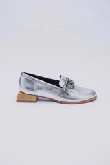 Mocasines de cuero en tono bronce metalizado, con detalle de aplique metálico dorado en el empeine y taco cuadrado bajo de madera.