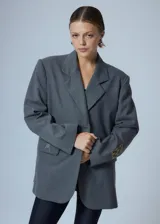 Saco sastrero oversize gris con bolsillos delanteros, forro de tafeta a tono, bordado en la tapa del bolsillo y etiqueta RENÉE tejida.