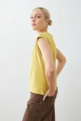 Remera color pistacho con cuello en V y botones decorativos en los hombros.