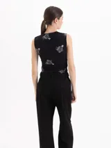 Top sin mangas de algodón negro con estampado de alfileres de gancho y fresas. Presenta escote cuadrado con detalle de puntilla y un pequeño moño central.