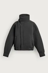 Cazadora boxy fit de tejido técnico gris oscuro, con cuello subido envolvente, cierre frontal asimétrico con cremallera oculta y bolsillos de vivo en la cadera.