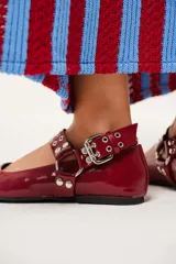 Balerinas color borgoña de charol con punta cuadrada, correa con hebilla y apliques metálicos.