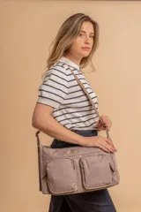 Bandolera de tafeta impermeable color beige, con dos bolsillos frontales con cierre y correa regulable. Diseño práctico y liviano ideal para uso diario.