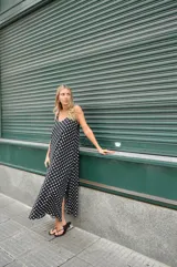 Vestido largo de crepe con estampado de lunares negros sobre fondo blanco. Presenta un diseño de corte holgado con breteles finos y escote redondeado.