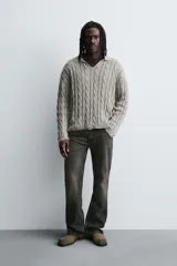 Polo de algodón tejido con estructura de trenzas, cuello solapa con abertura frontal en V y manga larga. Presenta acabados en rib con efecto roto en puños, cuello y ruedo.