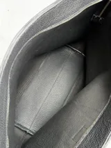 Cartera tipo tote de cuero genuino color marrón oscuro con textura de reptil. Cuenta con doble asa de hombro, cierre superior y un dije colgante de cuero a tono.