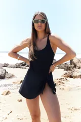 Traje de baño entero negro con escote redondo y falda corta con nudo lateral.