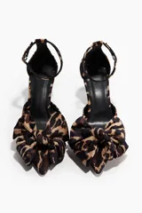 Zapato de tacón fino con pulsera ajustable al tobillo, confeccionado en velour con estampado animal print. Presenta una moña decorativa en la punta fina y forro interior de satén.