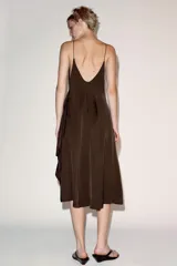 Vestido midi de viscosa color marrón, con escote en pico, tirantes finos y bajo asimétrico con volantes.