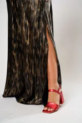 Vestido largo con estampado abstracto en tonos dorados y negros, escote en V, corte en la cintura y aberturas laterales.