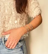 Brazalete rígido color plateado, de metal, con cuatro aros finos unidos entre sí.