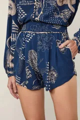 Short de tiro alto con cintura elastizada fruncida, bolsillos laterales y estampado integral de dragones y flores sobre base azul.