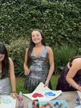 Vestido corto negro con estampado de plumas doradas, escote en V, breteles finos cruzados en la espalda, cut-outs laterales y volado en el ruedo.