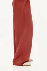 Pantalón de punto pesado color terracota, de corte amplio y pernera recta. Cuenta con cintura elástica revestida y pliegues frontales.