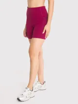 Calza corta deportiva de tiro alto, color bordó, con bolsillos laterales y banda de silicona para mayor sujeción.