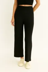 Pantalón negro de tiro alto, corte ancho y largo al tobillo, confeccionado en tejido con textura plisada o arrugada.