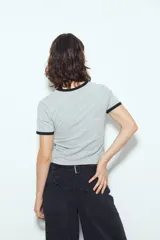 Remera cropped blanca de manga corta, con cuello redondo y terminaciones en contraste de color marrón en cuello y mangas. Inspirada en los clásicos de los años 80.