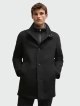 Abrigo corto de paño en color negro, con cierre frontal de botones y cuello alto con pieza interior desmontable con cierre. Presenta un diseño estructurado y elegante.