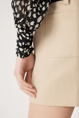 Camisa de manga larga con estampado de manchas blancas sobre fondo negro, confeccionada en tejido semitransparente. Presenta cuello clásico, cierre frontal con botones ocultos y puños abotonados.