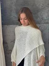 Ruana Clara tejida a mano con hilo liviano, de color blanco, con diseño amplio y con movimiento, ideal para salidas de verano.
