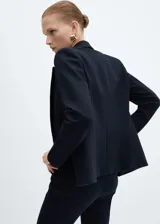 Blazer negro entallado de punto roma con solapas de muesca, hombros estructurados, abertura posterior y dos bolsillos de ribete delanteros.