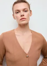 Chaqueta de punto entallada color tostado, con cuello en pico y cierre frontal de botones dorados efecto joya. Presenta mangas largas y un diseño estructurado.