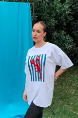 Remerón de algodón blanco con corte oversize y cuello redondo, que presenta un estampado frontal con diseño de una lata de sardinas sobre fondo de rayas.