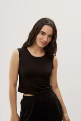 Top crop negro de calce ajustado, con escote redondo, diseño sin mangas y detalles de ojales metálicos decorativos en los hombros.
