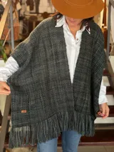 Ruana gris tejida en telar con lana merino pura, de diseño abierto y corte amplio, con flecos en el borde inferior.