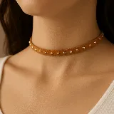 Gargantilla choker marrón de gamuza con tachas doradas.