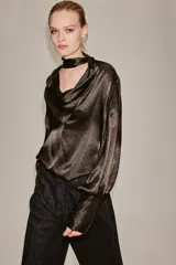 Blusa de seda color marrón oscuro con estampado geométrico sutil. Presenta un diseño de cuello fluido tipo pañuelo, manga larga con puños anchos y una caída suave y elegante.