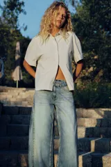 Camisa oversize de popelina con estampado de rayas verticales en tonos blanco y amarillo, cuello de solapa, manga corta con vuelta y cierre frontal de botones.