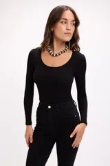 Body de manga larga en color negro, confeccionado en tejido de algodón elastizado con textura acanalada. Presenta un escote redondo amplio y un diseño ajustado al cuerpo.