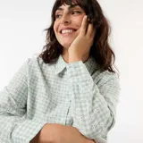 Camisa de manga larga color verde menta con estampado de cuadros vichy y delicado bordado inglés floral. Presenta cuello camisero clásico, cierre frontal abotonado oculto y terminaciones onduladas en el ruedo.