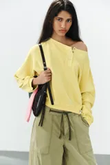 Sudadera de algodón con efecto lavado en color amarillo, cuello barco, abertura frontal con botones a presión y manga larga.