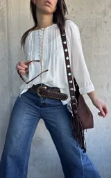 Blusa oversize de color blanco con diseño romántico y bohemio, confeccionada con detalles de encaje y botones forrados en el frente. Cuenta con mangas largas.