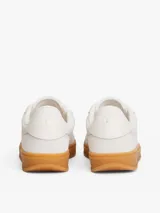 Zapatillas de corte bajo Tommy Hilfiger de inspiración retro, confeccionadas en ante color blanco con suela de goma color caramelo. Presentan monograma TH tonal en el lateral, detalles de ventilación en la puntera y cierre con cordones.
