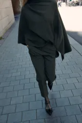 Pantalón tobillero gris oscuro de tiro alto con costuras marcadas en delantero y espalda, bolsillos delanteros de vivo y cierre frontal con cremallera, botón interior y gancho metálico.