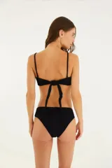 Bikini negro con textura. Top bandeau con detalle metálico central. Bombacha de cintura levemente alta.
