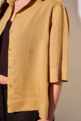 Camisa de lyocell color mostaza, de corte holgado, mangas cortas y cierre frontal con botones.
