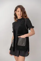 Chaleco de cuero negro tipo gamuza, con bolsillos frontales de cuero liso en contraste y detalles de costuras artesanales en bordes y bolsillos.