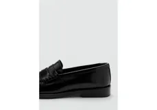 Zapato tipo mocasín de cuero vacuno color negro, con diseño de punta redonda, costuras visibles y detalle de antifaz en el empeine.