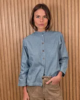 Camisa de algodón color blanco, con cuello alto con volados, mangas tres cuartos con detalles de bordado ingles y cierre frontal con botones de nácar.