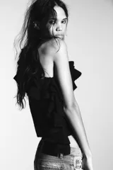 Jersey de punto con diseño asimétrico de un solo hombro, decorado con volantes en el escote y lateral. Presenta manga larga y corte ajustado con puños y ruedo acanalados.